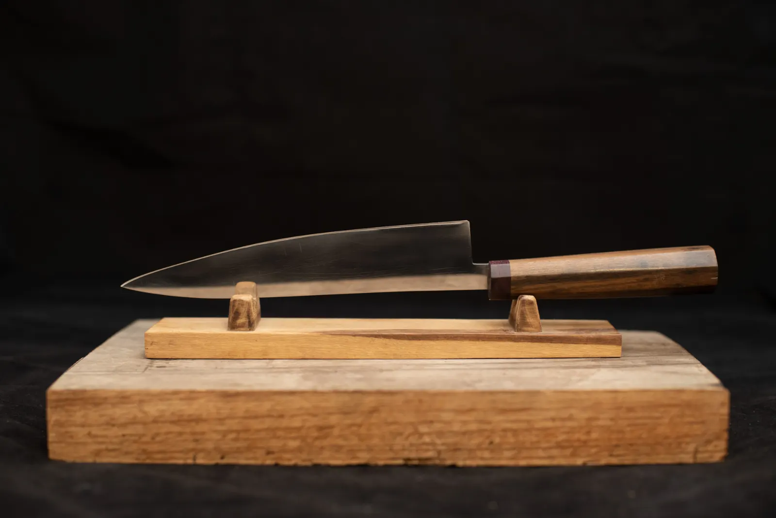 Cuchillo de cocina artesanal sobre soporte de madera