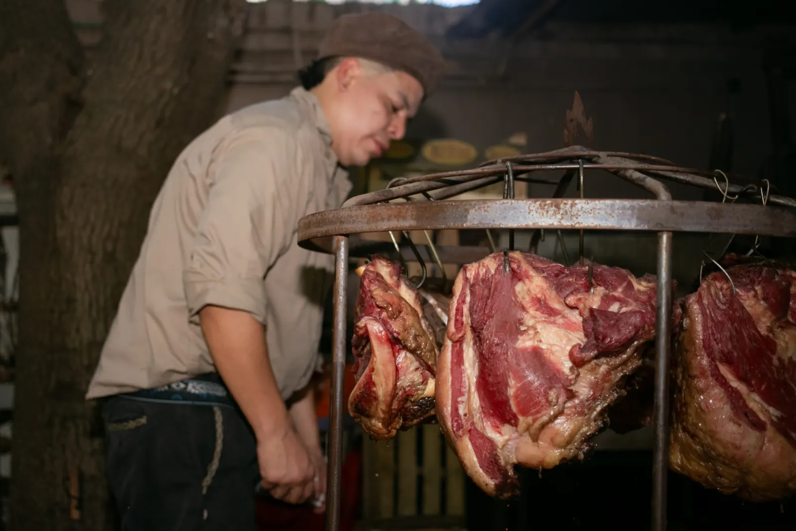 Josué junto a las carnes colgadas del asador