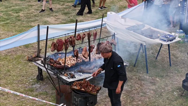 Parrillero de EstaqueameLaVaca cocinando carnes al gancho en un evento masivo al aire libre