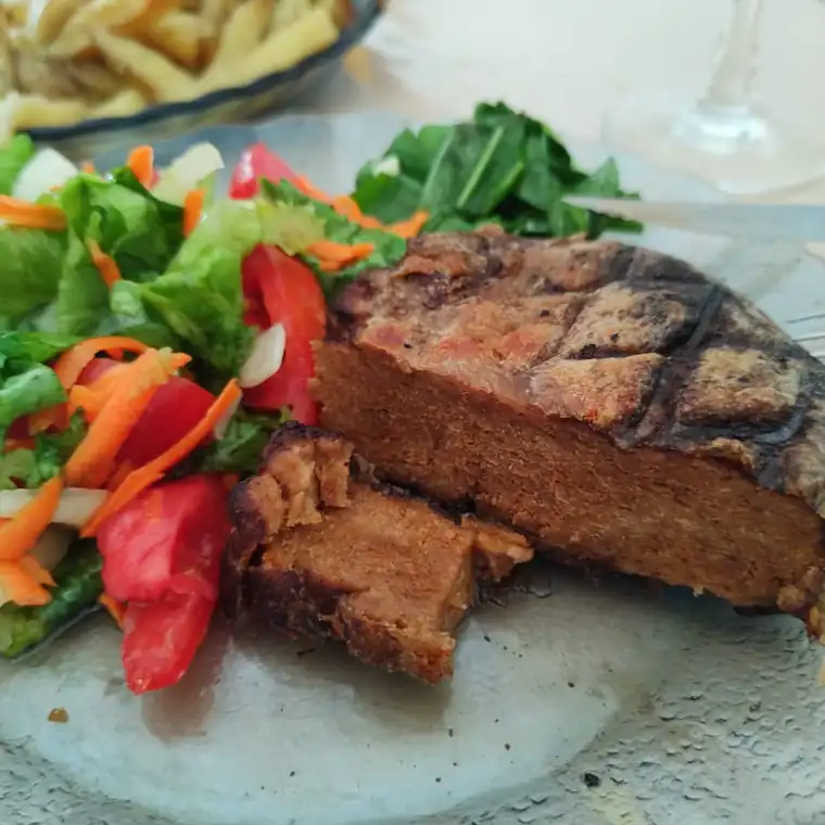 Seitán a la parrilla en rodajas, servido con ensalada, papas y verduras